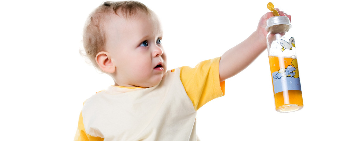 Baby at Georgie Porgies nursery in Denton offering bottle to carer